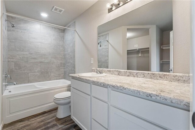 bathroom with wood finished floors, shower / bathing tub combination, vanity, toilet, and visible vents