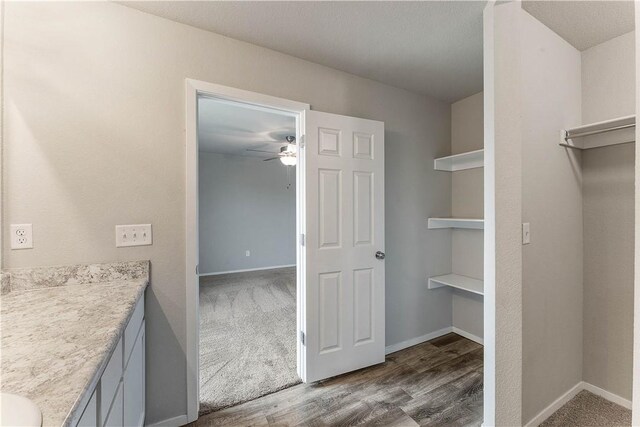 bathroom featuring ceiling fan, baseboards, vanity, and wood finished floors