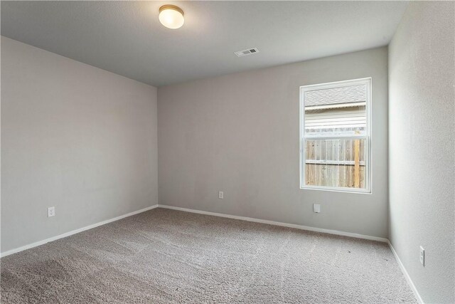 empty room with baseboards, visible vents, and carpet