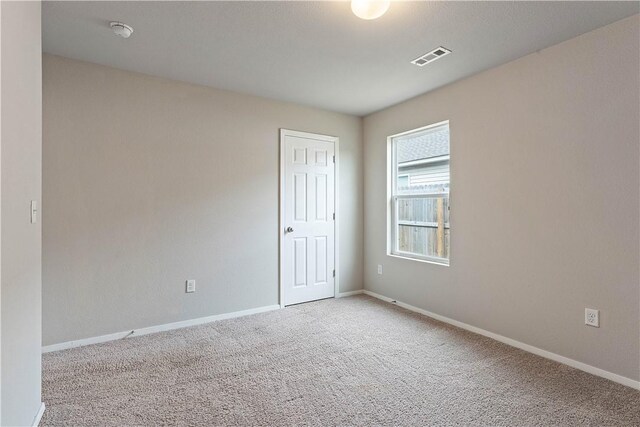 carpeted empty room featuring baseboards and visible vents
