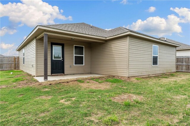 back of house with a yard, roof with shingles, a patio, and a fenced backyard