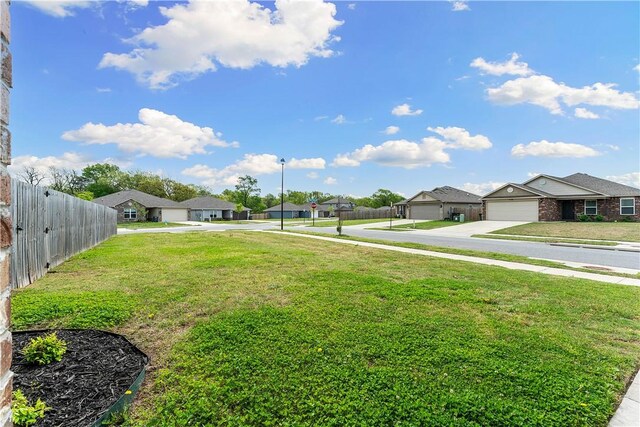 view of yard featuring fence, a residential view, and driveway
