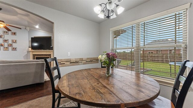 505 Blair Cir, Pea Ridge, AR 72751 - dining room featuring vaulted ceiling, wood finished floors, ceiling fan with notable chandelier, and a fireplace