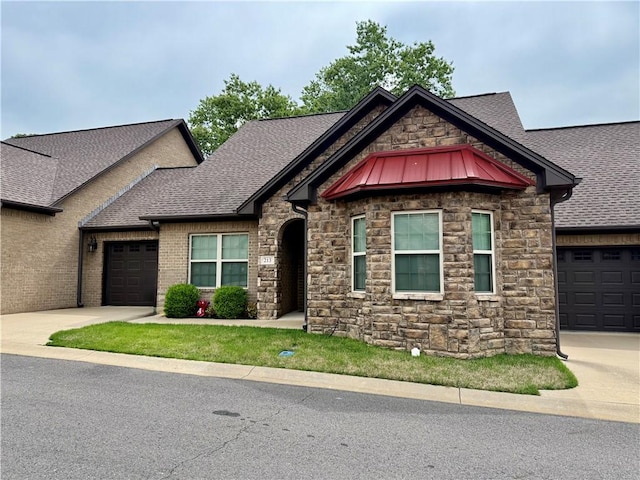 craftsman-style house featuring concrete driveway, an attached garage, a standing seam roof, stone siding, and roof with shingles