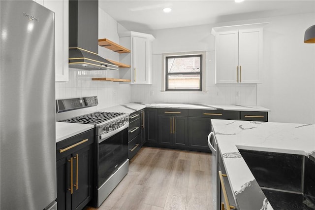 220 N C St, Rogers, AR 72756 - kitchen featuring stainless steel appliances, wall chimney exhaust hood, white cabinetry, light wood-type flooring, and light stone countertops