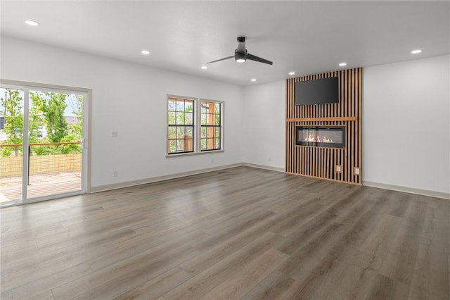 220 N C St, Rogers, AR 72756 - unfurnished living room featuring plenty of natural light, a ceiling fan, a glass covered fireplace, wood finished floors, and recessed lighting