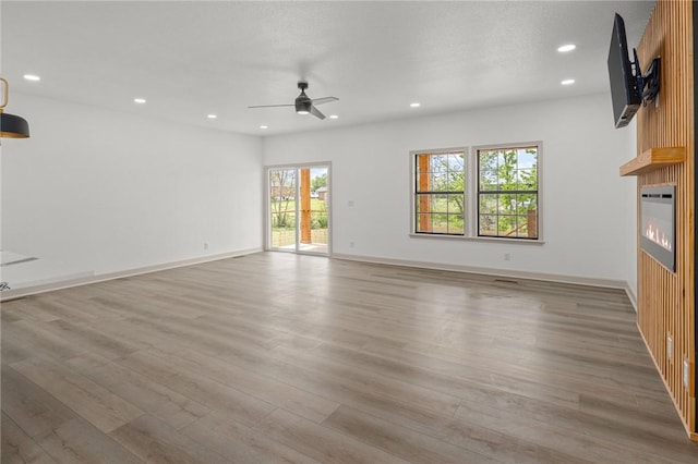 220 N C St, Rogers, AR 72756 - unfurnished living room featuring ceiling fan, a large fireplace, light wood-style floors, recessed lighting, and baseboards