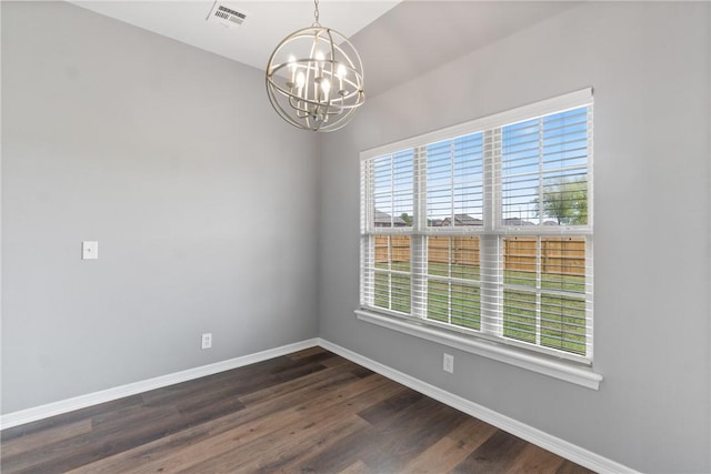 empty room featuring a chandelier, baseboards, and dark wood-type flooring