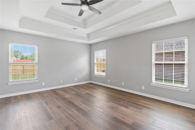 unfurnished room with a raised ceiling, crown molding, wood finished floors, healthy amount of natural light, and a ceiling fan