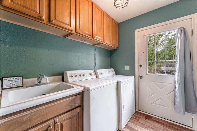 laundry area featuring separate washer and dryer, cabinet space, a sink, and light wood finished floors