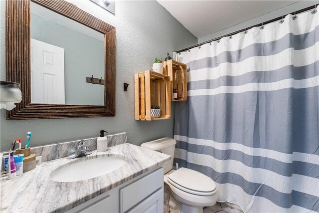 bathroom featuring curtained shower, a textured wall, toilet, and vanity