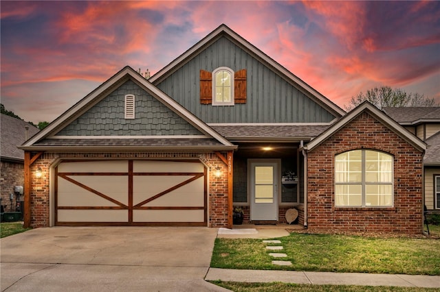 craftsman house with brick siding, a yard, an attached garage, and driveway