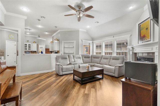 living area with ceiling fan, ornamental molding, visible vents, and light wood-style flooring