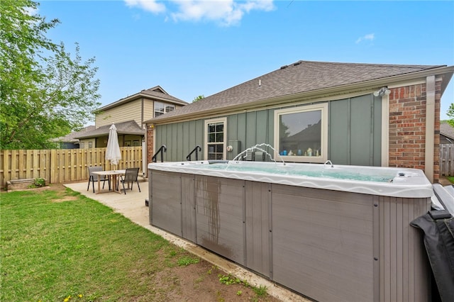 back of property with board and batten siding, fence, a hot tub, and roof with shingles