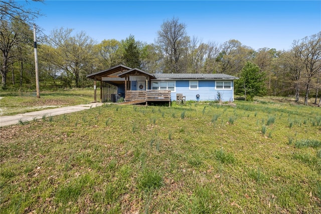 view of front of house featuring concrete driveway, a carport, a deck, and a front yard