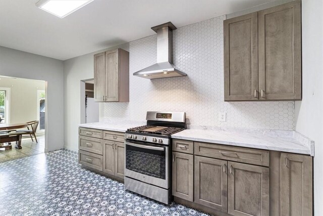 501 SE Main St, Gravette, AR 72736 - kitchen with wall chimney exhaust hood, stainless steel range with gas stovetop, light floors, and backsplash