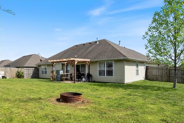 rear view of property with a fenced backyard, a pergola, a fire pit, and a lawn