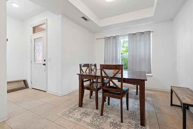 dining area featuring a tray ceiling, visible vents, baseboards, and light tile patterned floors