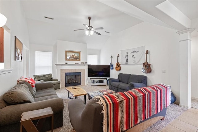 tiled living room featuring vaulted ceiling, visible vents, decorative columns, a tiled fireplace, and ceiling fan