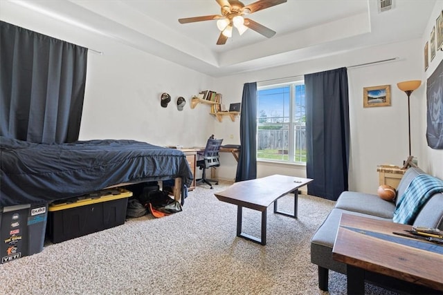 bedroom with visible vents, a tray ceiling, carpet floors, and ceiling fan