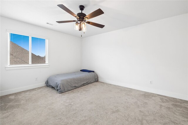 unfurnished bedroom featuring baseboards, visible vents, ceiling fan, and carpet flooring