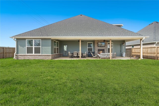 rear view of property featuring a lawn, a ceiling fan, brick siding, and a fenced backyard