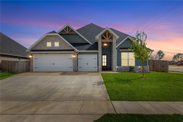 craftsman house featuring a front lawn, driveway, stone siding, an attached garage, and fence