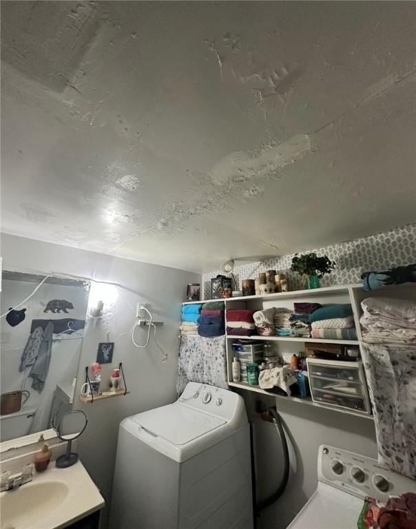 clothes washing area with laundry area, a sink, and washer / clothes dryer