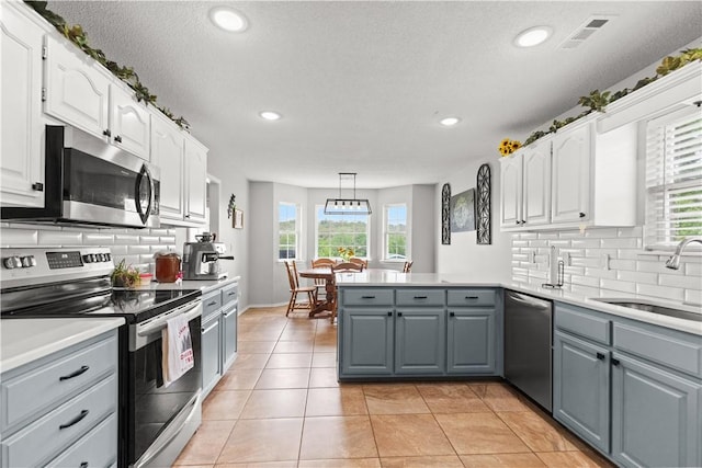 424 W Tanner Dr, Fayetteville, AR 72701 - kitchen featuring a sink, a peninsula, gray cabinetry, white cabinets, and appliances with stainless steel finishes