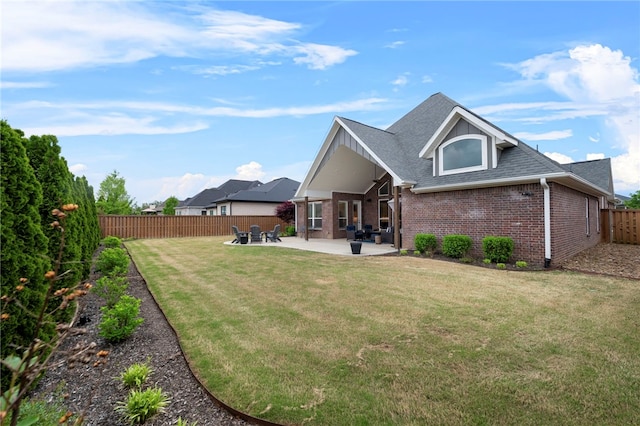 back of house featuring a fenced backyard, brick siding, a shingled roof, a patio area, and a lawn