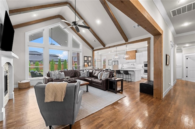 living area featuring a ceiling fan, visible vents, wood finished floors, and high vaulted ceiling