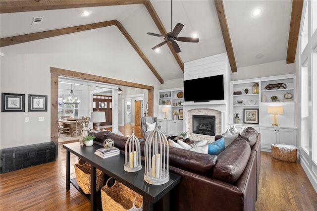 living room featuring beamed ceiling, visible vents, a fireplace, wood finished floors, and ceiling fan with notable chandelier