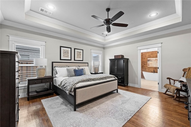 bedroom featuring crown molding, visible vents, wood finished floors, and a raised ceiling