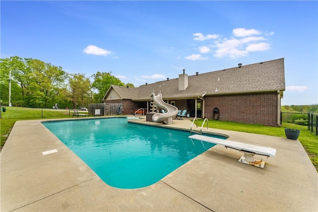 view of pool featuring a lawn, a fenced in pool, a water slide, and a patio area