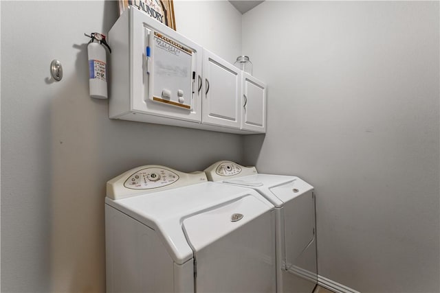 clothes washing area featuring cabinet space and washer and clothes dryer