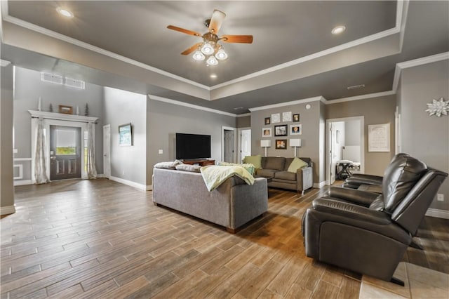 living room with a raised ceiling, ceiling fan, baseboards, recessed lighting, and wood finished floors