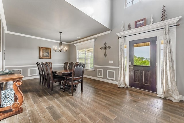 dining room with wood finished floors, ornamental molding, a notable chandelier, and wainscoting