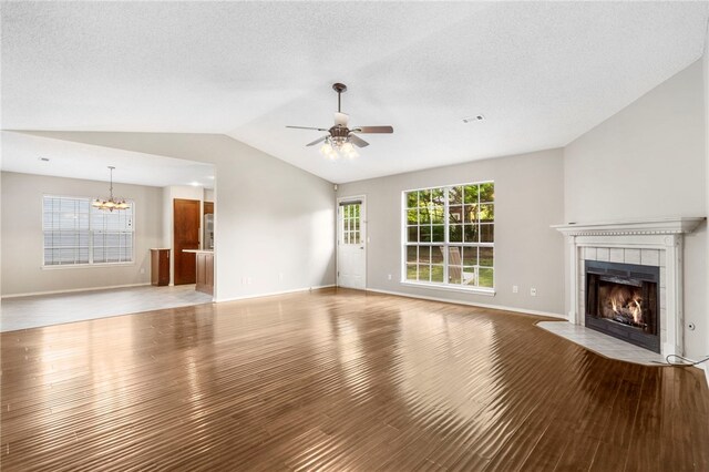 1600 N Stable Ave, Fayetteville, AR 72703 - unfurnished living room with a tile fireplace, wood finished floors, visible vents, lofted ceiling, and ceiling fan with notable chandelier