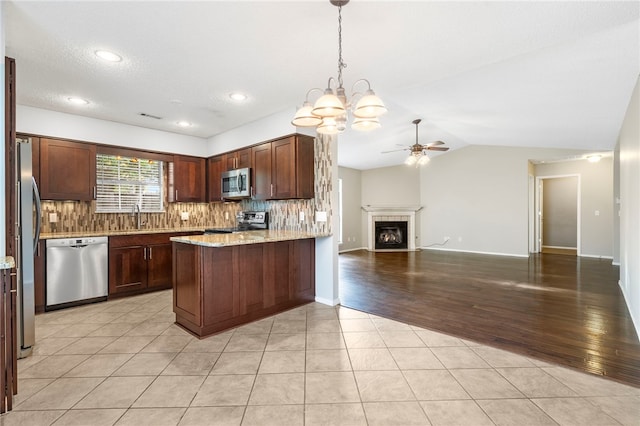 1600 N Stable Ave, Fayetteville, AR 72703 - kitchen featuring backsplash, a peninsula, appliances with stainless steel finishes, open floor plan, and ceiling fan with notable chandelier