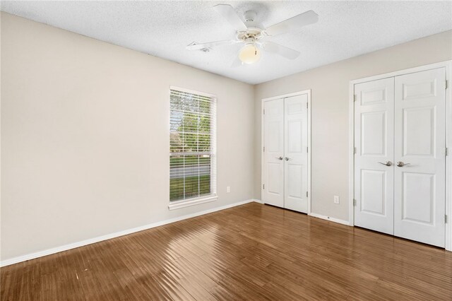 1600 N Stable Ave, Fayetteville, AR 72703 - unfurnished bedroom with wood finished floors, multiple closets, baseboards, a ceiling fan, and a textured ceiling