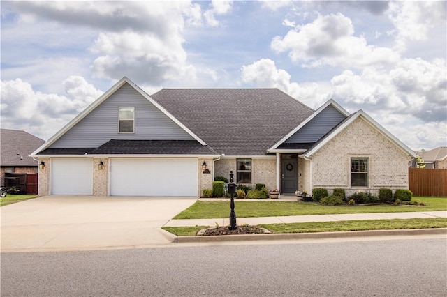 craftsman house with a front yard, fence, concrete driveway, and brick siding