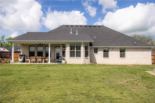 rear view of property with fence, a yard, roof with shingles, and a patio area
