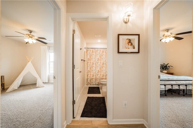 hallway featuring carpet flooring, tile patterned floors, and baseboards