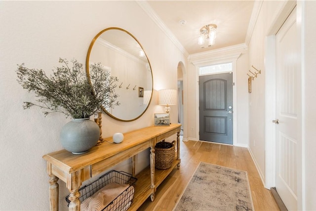 doorway featuring baseboards, arched walkways, light wood-style floors, and crown molding