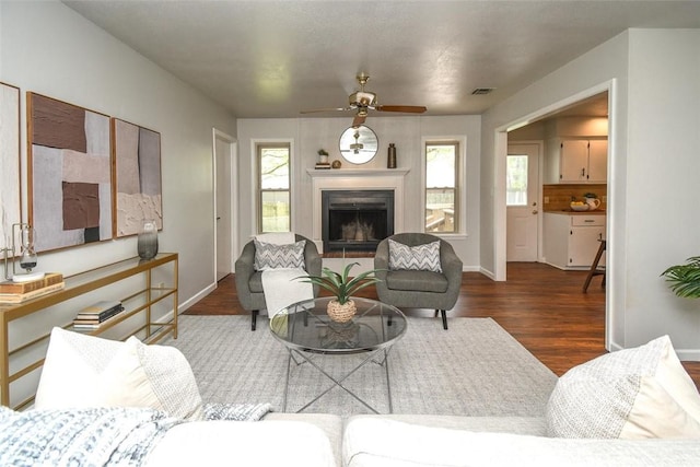 living room featuring wood finished floors, visible vents, ceiling fan, and plenty of natural light