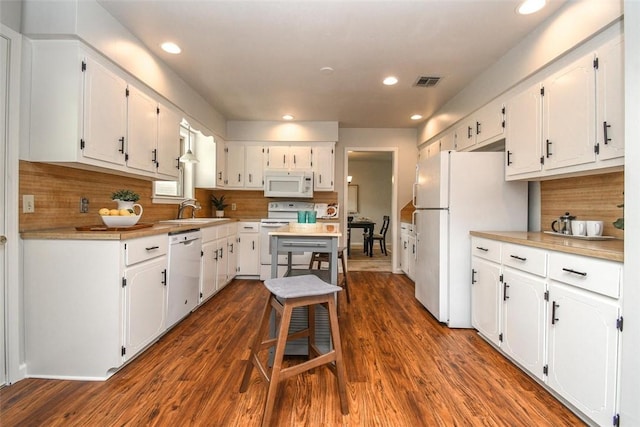 kitchen with visible vents, white appliances, white cabinets, and a sink