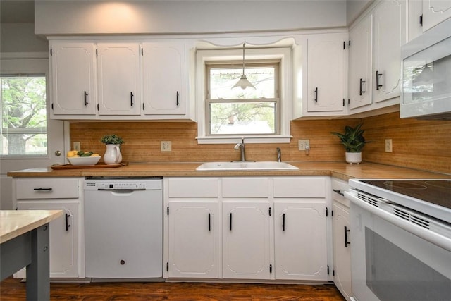 kitchen with a sink, white appliances, white cabinetry, backsplash, and light countertops