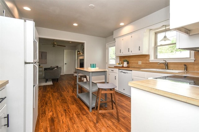 kitchen featuring white appliances, white cabinets, dark wood finished floors, and a sink