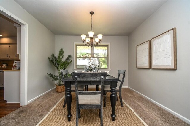 dining room with carpet floors, a chandelier, and baseboards