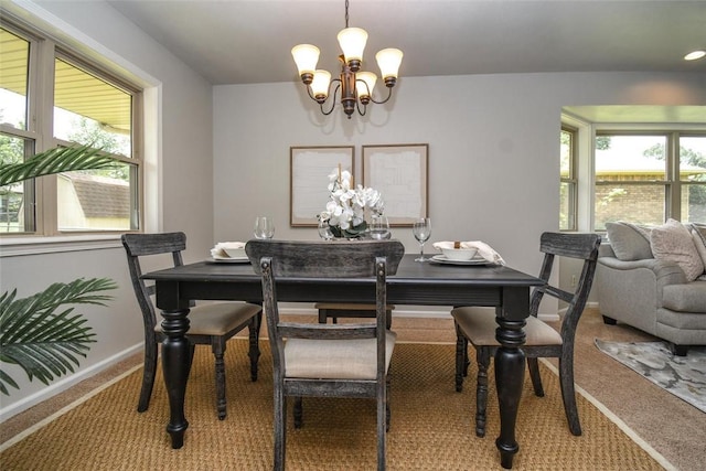 carpeted dining space with a notable chandelier and baseboards